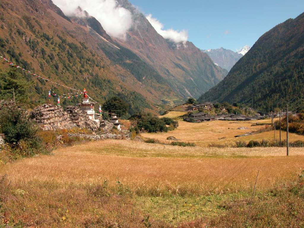 Manaslu 06 06 Lho The views now start to open up, but clouds obscured Manaslu and Manaslu North (7157m). I looked back at Lho (3180m), with the enormous mani wall on the left, and fields of barley in front. Note the electricity poles on the far right.